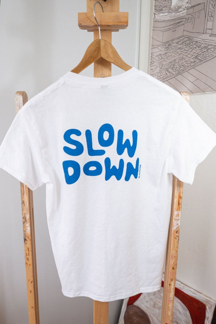 back of white slow-down t-shirt with blue screen printed "slow down" text across upper back