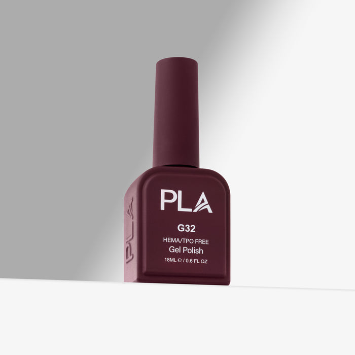 A bottle of PLA G32 HEMA/TPO Free Gel Polish in a deep burgundy shade, standing upright on a white surface against a gray background.