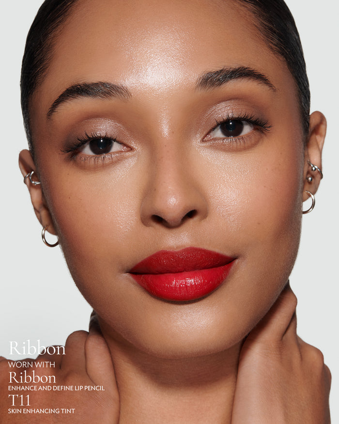 Close-up of a model with pillar-box red, Ribbon Rouge Experience Lipstick on, alongside Ribbon Enhance and Define Lip Pencil and T11 Enhancing Tint, with a neutral background