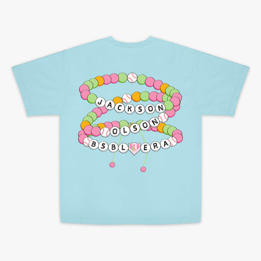 Light blue t-shirt with colorful letter beads and "Jackson Olson BSBL Era" text design on a white background