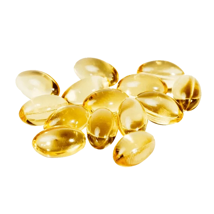 A high-angle view of fifteen amber CBN:CBD:THC 5:5:5 softgels arranged in a loose, circular pattern on a white surface.