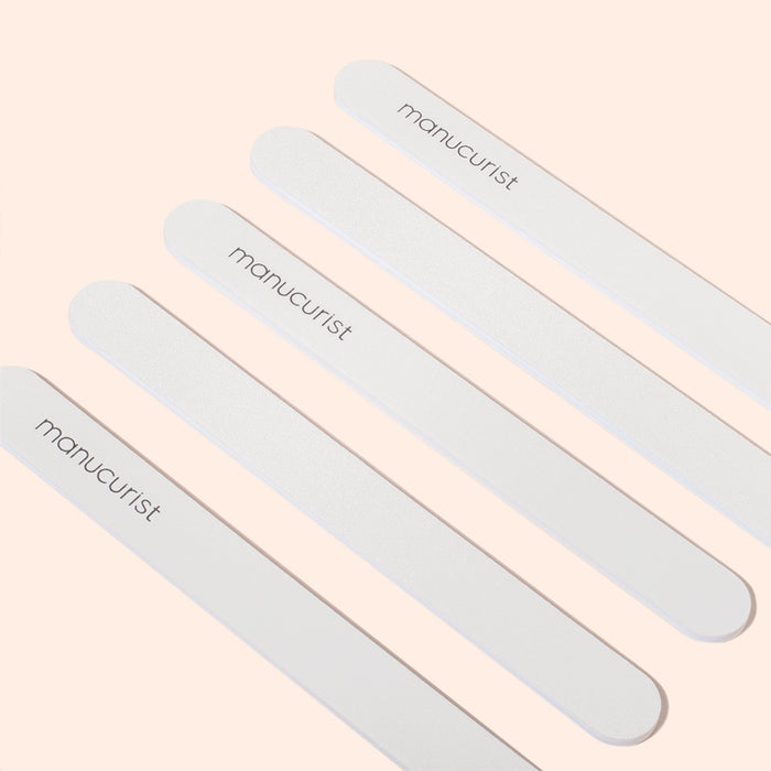 Five Manucurist Emery boards are arranged diagonally on a light beige background. Each file, featuring a fine grit surface, displays the brand name Manucurist printed in black letters.