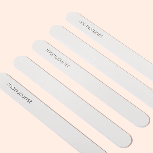 Five Manucurist Emery boards are arranged diagonally on a light beige background. Each file, featuring a fine grit surface, displays the brand name Manucurist printed in black letters.