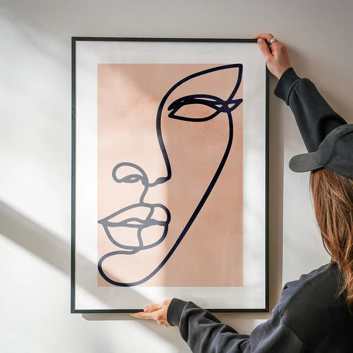 Face Study Line Art Watercolour Print being hung on a wall in a black frame