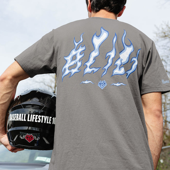 Back view of gray Flame Thrower tee showing blue and white BL101 flame letter graphic, model holding Baseball Lifestyle 101 racing helmet at side.