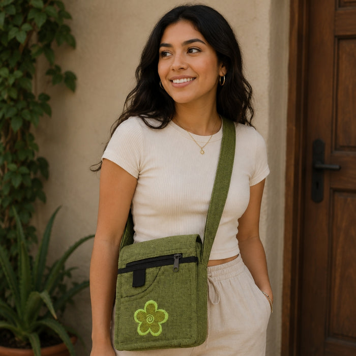 Woman holding a green crossbody bag with a flower design, standing in front of a wooden door.