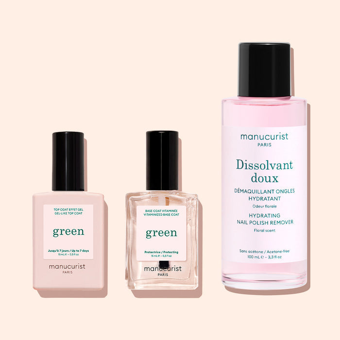 Three manicure products—a plant-based base coat, the Green Sunshine Top Coat from Manucurist for a gel effect finish, and a pink bottle of hydrating nail polish remover—are arranged side by side on a pale background.