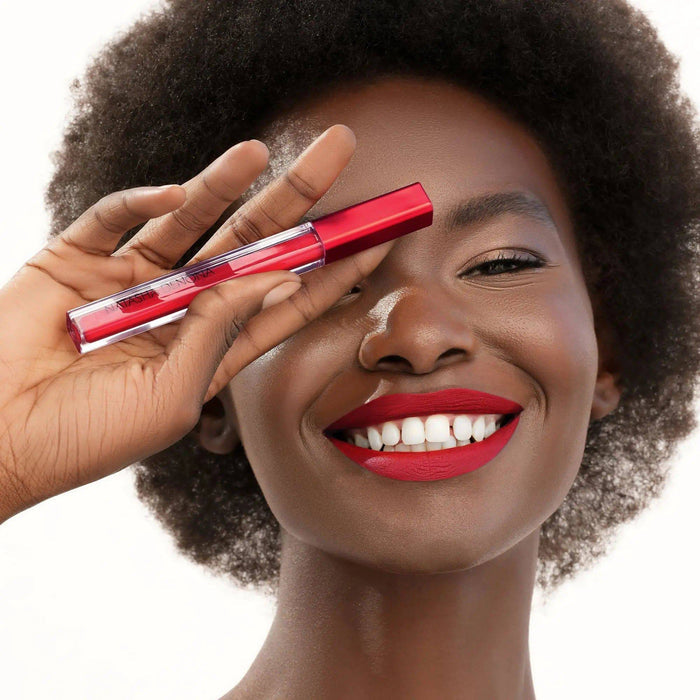 I Need a Rouge Matte Liquid Lipstick model look on a white background. The model is holding the product in her hand.