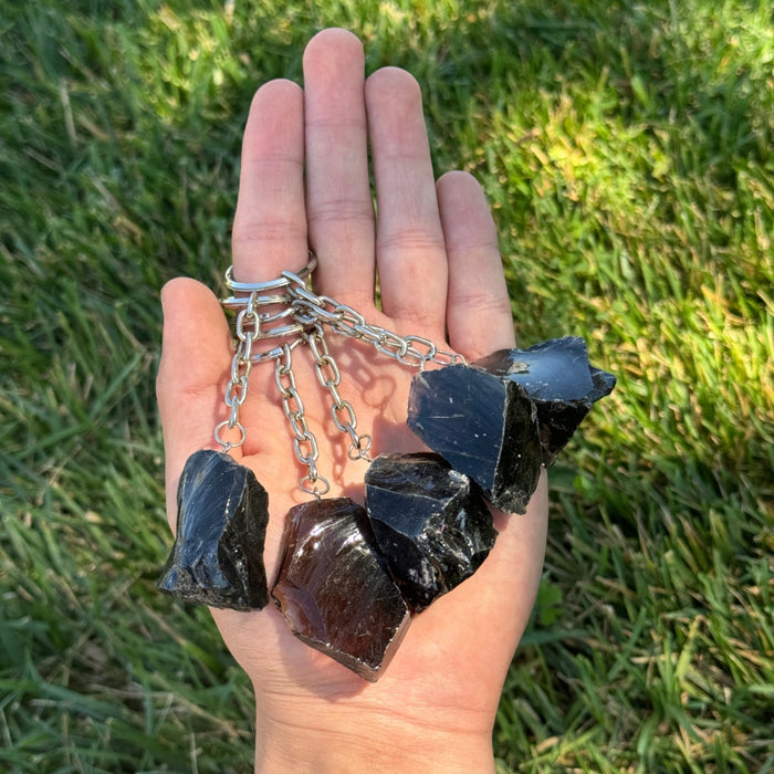 Hand holding a Black Obsidian Keychain  against a grassy background