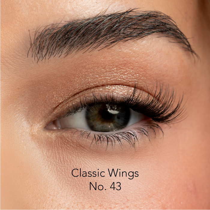 Close-up of an eye with false eyelashes labeled 'Classic Wings No. 43' on a neutral background