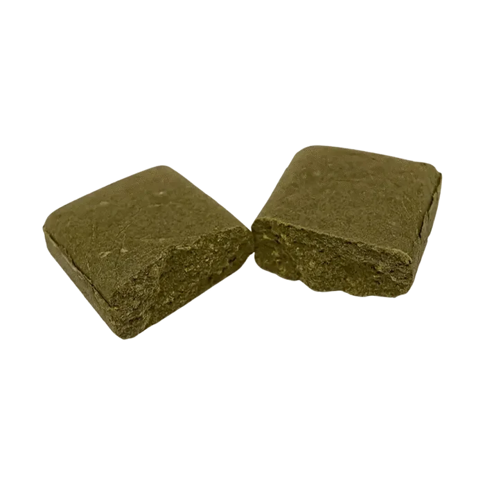 Close-up of a roughly rectangular piece of Moroccan Gold Hash against a plain white background.