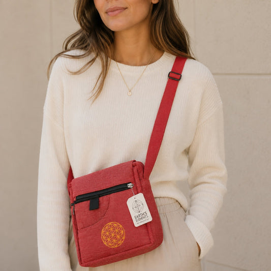 Person wearing a red crossbody bag with a visible brand tag against a neutral background