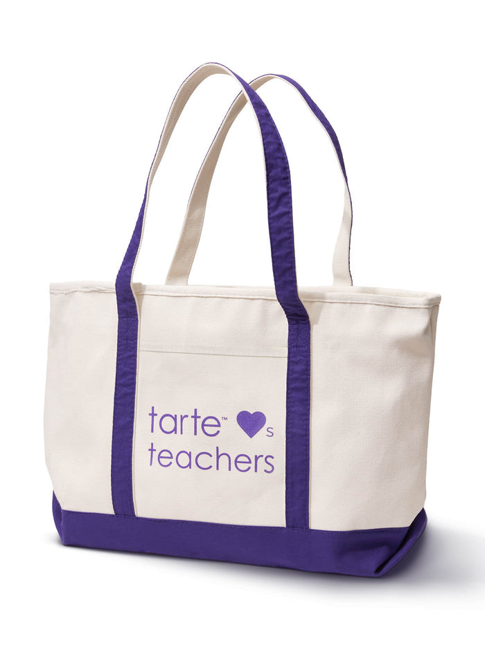 A beige tote bag with purple handles and accents stands upright on a white background. It features the text tarte ♥s teachers in purple on its front.
