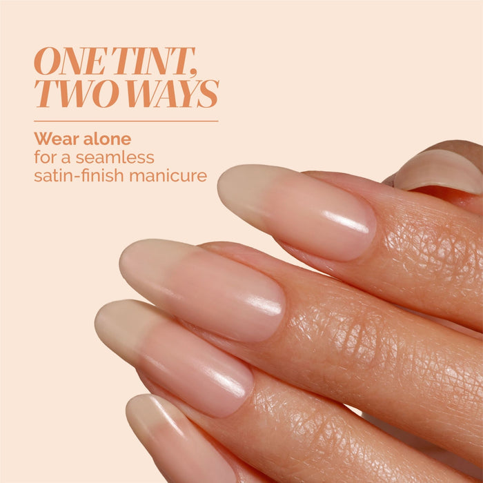 A close-up of a hand with long, natural nails in an apricot beige satin tint. Text: “LONDONTOWN Tinted Fortifying Ridge Filler - Apricot Beige smooths ridges and adds a seamless hint of color for a flawless manicure.”.