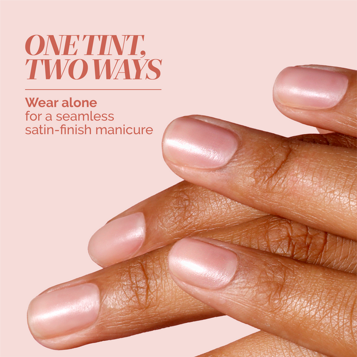 Close-up of hands with neatly manicured nails painted in LONDONTOWN’s Tinted Fortifying Ridge Filler - Petal Pink. Text reads: “One hint of tint, two ways. Wear alone to smooth ridges and get a seamless satin-finish manicure.”.