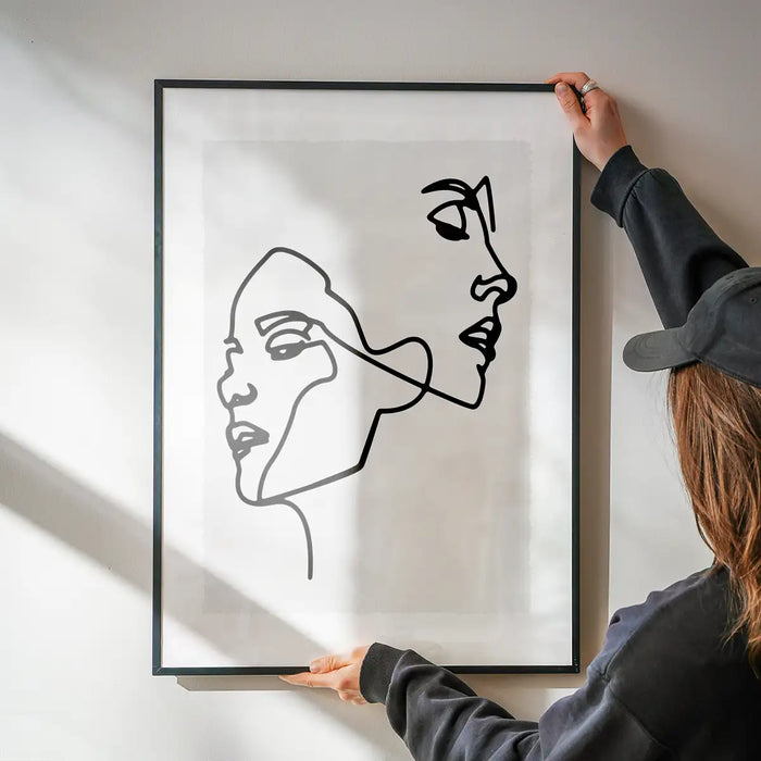 Two Faces Study Line Art Print being hung on a wall in a black frame
